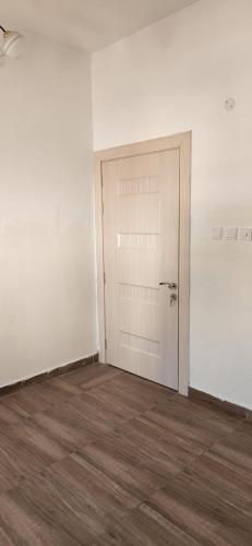 ein leeres Zimmer mit einer Tür und einem Holzboden in der Unterkunft مسقط الوادي الكبير in Wādī Kabīr