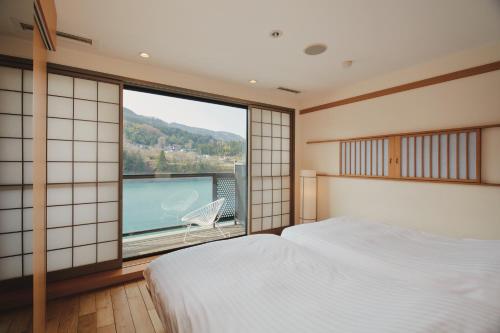 a bedroom with a bed and a large window at River Retreat Garaku in Toyama