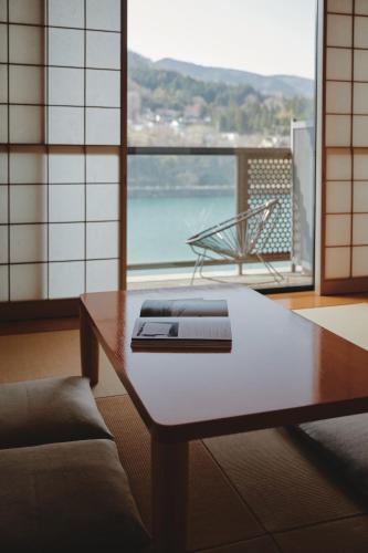 a room with a table and a couch and a window at River Retreat Garaku in Toyama
