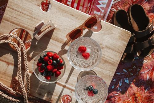 a table with two glasses of fruit and a bowl of berries at On The Sand at Mollymook Beach in Mollymook