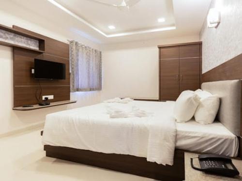a hotel room with a bed and a television at Nectar Nest in Coimbatore