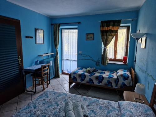 a blue bedroom with two beds and a desk at Casa Omnia B&B in Castellamonte