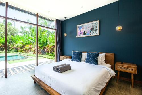 ein Schlafzimmer mit einem großen Bett und einem großen Fenster in der Unterkunft New 5br Villa, Enclosed Lounge, Canggu Oasis in Canggu