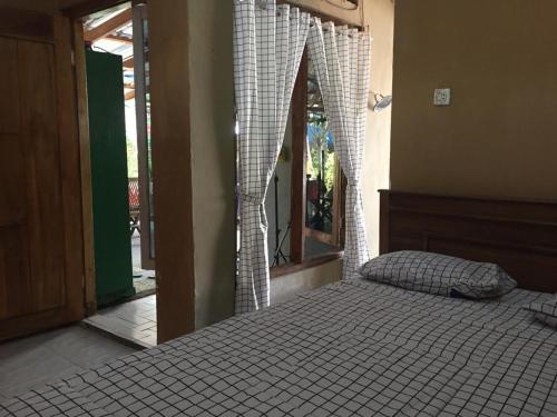 a bedroom with a bed and a window with curtains at De Ikut Bojo Homestay in Magelang
