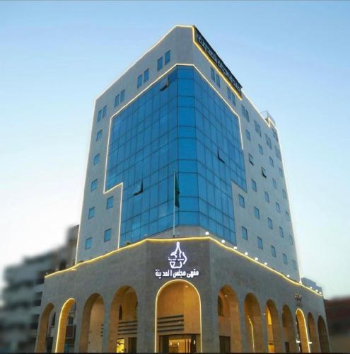 un edificio de cristal alto con un cartel. en Hayat Al madinah Hotel فندق حياة المدينة, en Medina