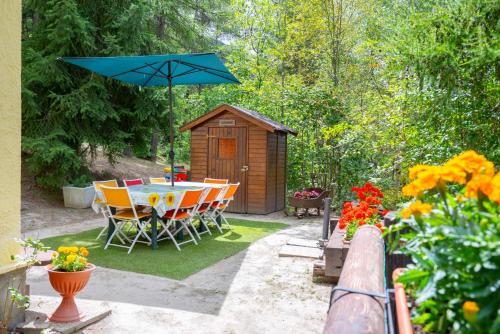 a table and chairs with a blue umbrella in a garden at La casa dello scoiattolo CIR COMUNALE N 20 in Gressan