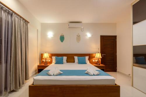 a bedroom with a large bed with blue pillows at Sahaj Holiday Apartments in Baie Sainte Anne
