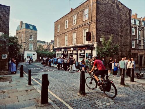 Um homem a andar de bicicleta numa rua em The Melville Hotel by Rokxy- Kings Cross em Londres