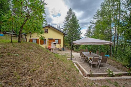 a table with chairs and an umbrella in front of a house at La casa dello scoiattolo CIR COMUNALE N 20 in Gressan