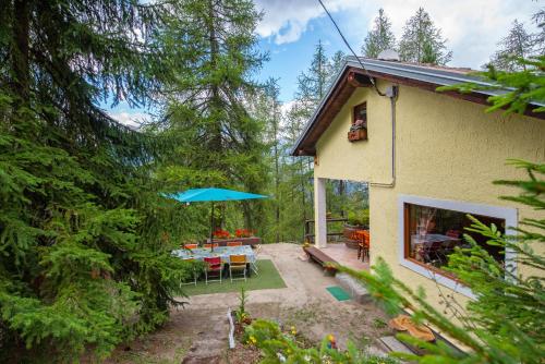 a house with a patio with a table and an umbrella at La casa dello scoiattolo CIR COMUNALE N 20 in Gressan