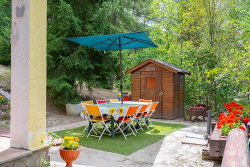 a table and chairs with a blue umbrella in a backyard at La casa dello scoiattolo CIR COMUNALE N 20 in Gressan