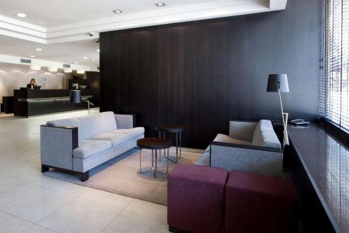 a lobby with a couch and chairs and a table at NH Lleida Pirineos in Lleida