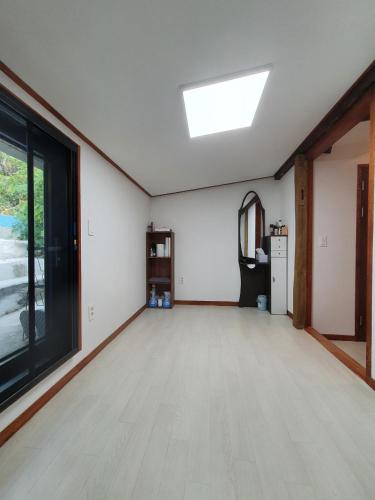 an empty living room with a skylight and wood floors at Yachtie Inn Mokpo in Mokpo