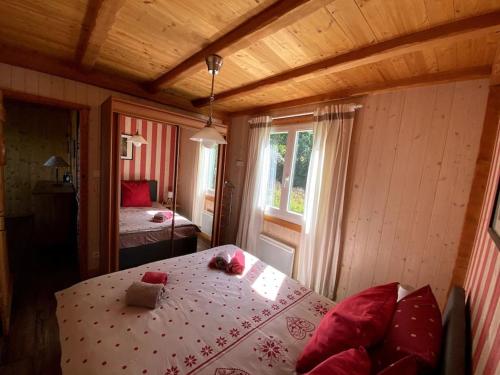 a bedroom with a table and a bed with red pillows at Le chalet des coeurs in Le Tholy