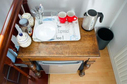 una mesa de madera con un plato y tazas. en Komfortowe przestronne pokoje z prywatnymi łazienkami blisko Warszawy i Suntago, en Milanówek