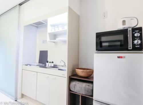 a kitchen with a microwave on top of a refrigerator at NEW! Relaxing Prime Unit in the Heart of Shibuya! in Tokyo