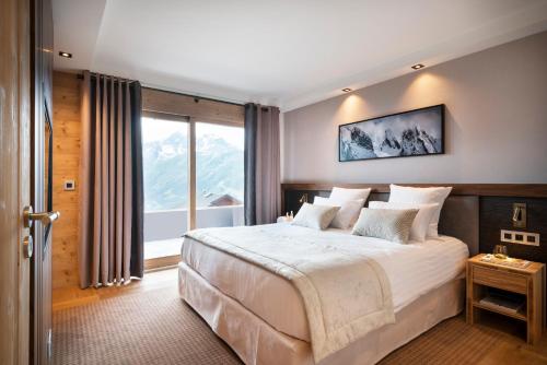 a bedroom with a large bed and a large window at Hôtel Alpen Lodge in La Rosière