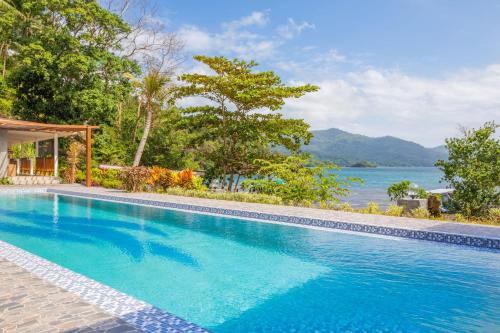 a swimming pool with a view of the water at Thalassa Dive Resort Lembeh in Airtembago