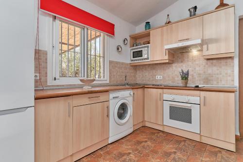 a kitchen with wooden cabinets and a washer and dryer at Villa Torrox Costa con Piscina in Torrox