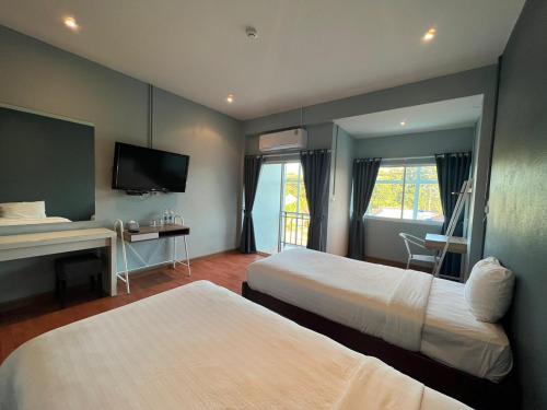 um quarto de hotel com duas camas e uma televisão em A Hotel Cozy em Ban Pa Sak