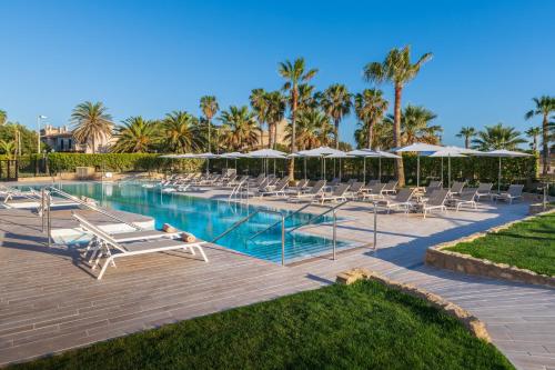 a swimming pool with lounge chairs and umbrellas at Elba Costa Ballena Beach & Thalasso Resort in Costa Ballena