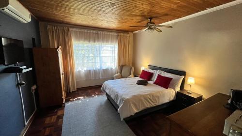 een slaapkamer met een bed met rode kussens en een raam bij 298 on 34th in Pretoria