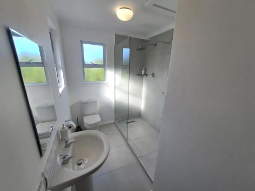 a white bathroom with a sink and a shower at Atlantic Dream Beachfront Villa in Scarborough