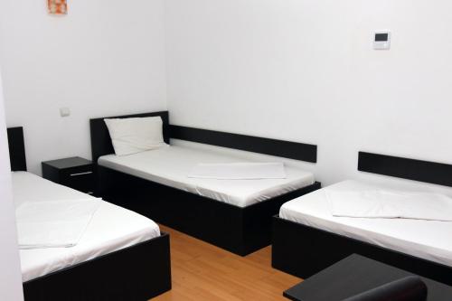 three beds in a room with white walls at Pensiunea La Tase in Calafat
