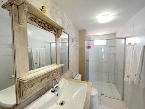 a bathroom with a sink and a shower and a mirror at Apartamento Confortável - Porto das Dunas - Perto do Beach Park in Aquiraz