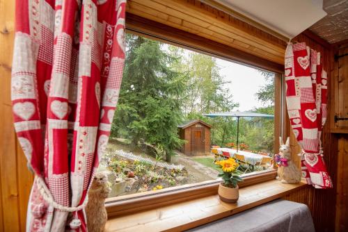 a window with a red and white curtain and flowers at La casa dello scoiattolo CIR COMUNALE N 20 in Gressan