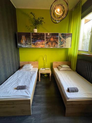 2 łóżka w pokoju z zielonymi ścianami w obiekcie Apartament Jagiellonska w mieście Sosnowiec