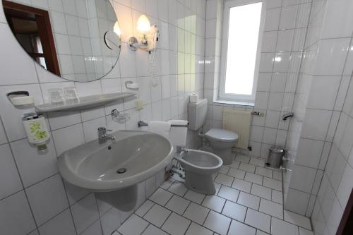 a white bathroom with a sink and a toilet at Hotel Glück Auf & Bürgerkeller in Bad Grund