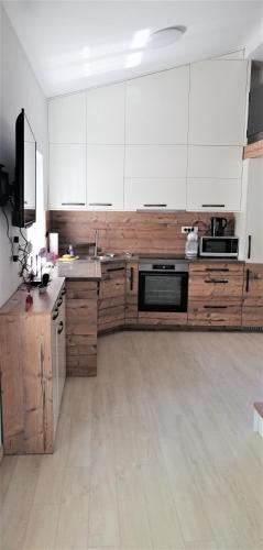 a kitchen with white cabinets and wooden floors at APARTMA NIKA in Pobegi
