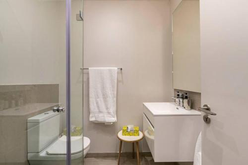 a white bathroom with a toilet and a sink at Stylish Apartment w/ inverter 1km 2Hyde Park in Johannesburg