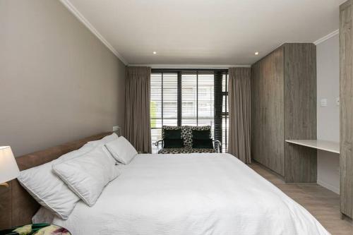 a bedroom with a large white bed and a window at Stylish Apartment w/ inverter 1km 2Hyde Park in Johannesburg