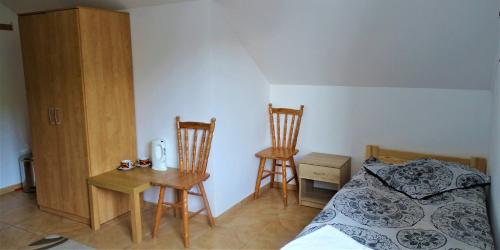 a bedroom with a bed and two chairs and a table at Mimoza Gospodarstwo Agroturystyczne in Bartoszyce
