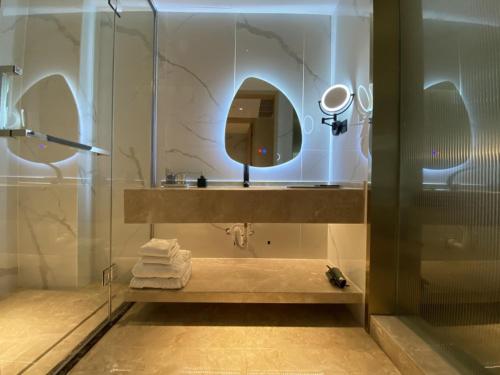 a bathroom with a sink and a shower with a mirror at Geli Hotel Bengbu Wanda Plaza Nanxiang City in Bengbu