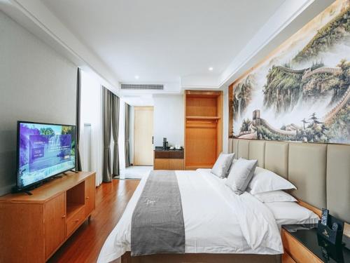 um quarto com uma cama grande e uma televisão de ecrã plano em GreenTree Eastern Hotel Anshun Anshun Zhenning Huangguoshu em Zhenning