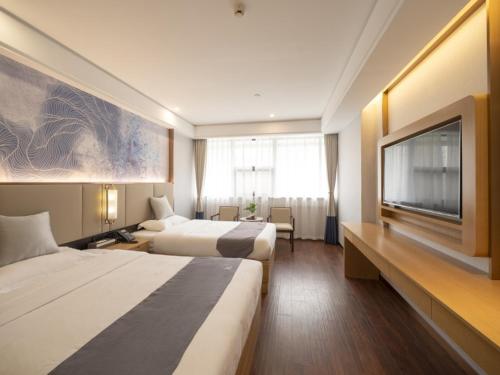 GreenTree Eastern Hotel Lihu Yuantouzhu Scenic Area في ووشي: غرفة فندقية بسريرين وتلفزيون بشاشة مسطحة