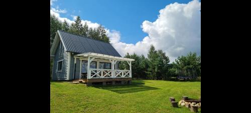 a small house with a porch on a grass field at Sunset House in Sulęczyno