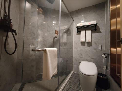 een badkamer met een douche, een toilet en handdoeken bij GreenTree Eastern Hotel Shenzhen Futian Civic Center Jingtan Subway Station in Shenzhen