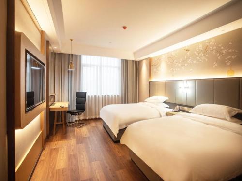 una camera d'albergo con 2 letti, una scrivania e una TV di GreenTree Eastern Hotel Anhui Xuancheng Guangde Old Cross Street a Guangde