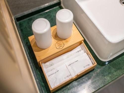 two white cups on a wooden tray in a vehicle at Deep Sleep Hotel Hangzhou Dajiang East Haide Xingang Center in Hangzhou