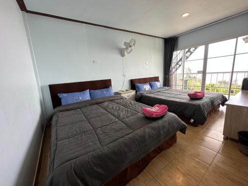 a bedroom with two beds with red pillows on them at สเตชั่นภูทับเบิก-บ้านดาดฟ้าทะเลหมอก in Ban Tha Kok Hai