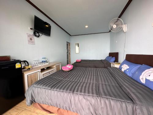 a bedroom with a large bed and a fan at สเตชั่นภูทับเบิก-บ้านดาดฟ้าทะเลหมอก in Ban Tha Kok Hai