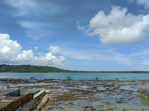 a large body of water with a blue sky and clouds at Friendly losmen in Lagudri