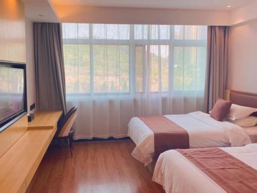 TaozhuangにあるGeli Hotel Zaozhuang High-Speed Railway Stationのベッド2台、薄型テレビが備わるホテルルームです。