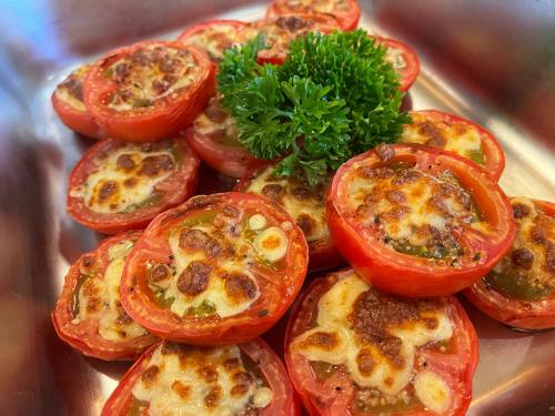 a pile of tomatoes on a plate with a green garnishment at Keypai Hotel Free Shuttle Bus to Canton Fair in Guangzhou