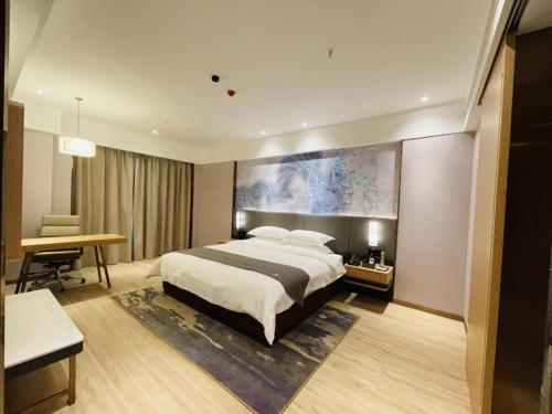 sypialnia z dużym łóżkiem i biurkiem w obiekcie GreenTree Eastern Guangxi Baise Wuzhong Sports Center High-Speed Railway Station 
