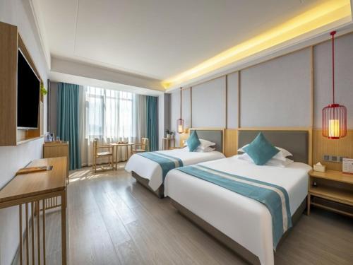 a hotel room with two beds and a desk at GreenTree Eastern Hotel Chuzhou Government East Garden Road in Chuzhou